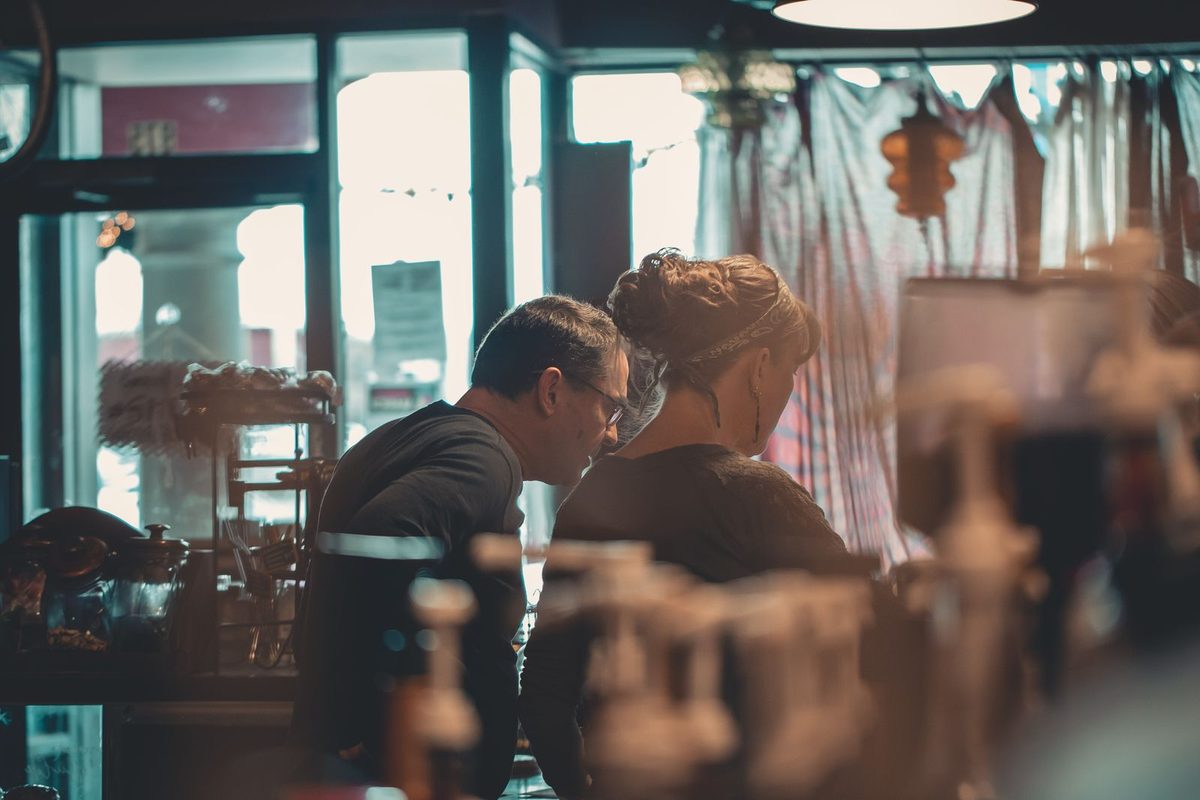 Two people working together behind the counter of a small shop